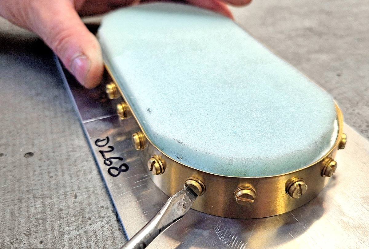 Close-up of an experienced tool maker adjusting a bespoke brass high-frequency welding tool.