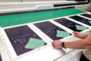 Operator aligning printed sheets on a Canon Arizona 1380 GT flatbed printer at Duraweld.