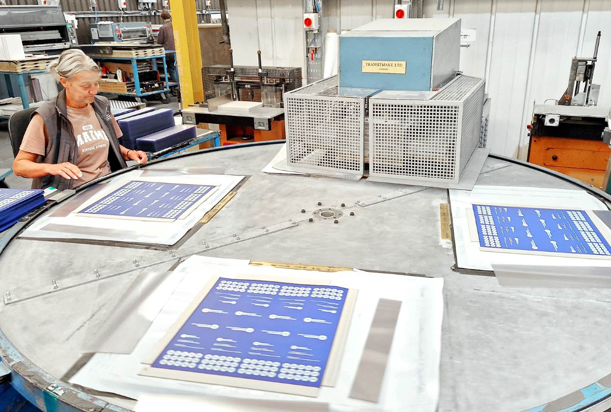 Operator loading printed PVC components onto a high-frequency rotary welding machine at Duraweld.