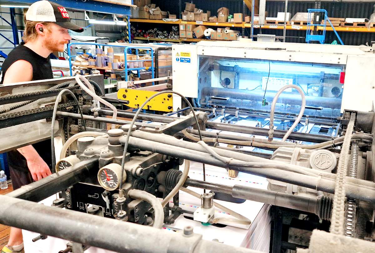Operator monitoring the Sanwa TRP-1060 automatic die-cutting and creasing machine at Duraweld.